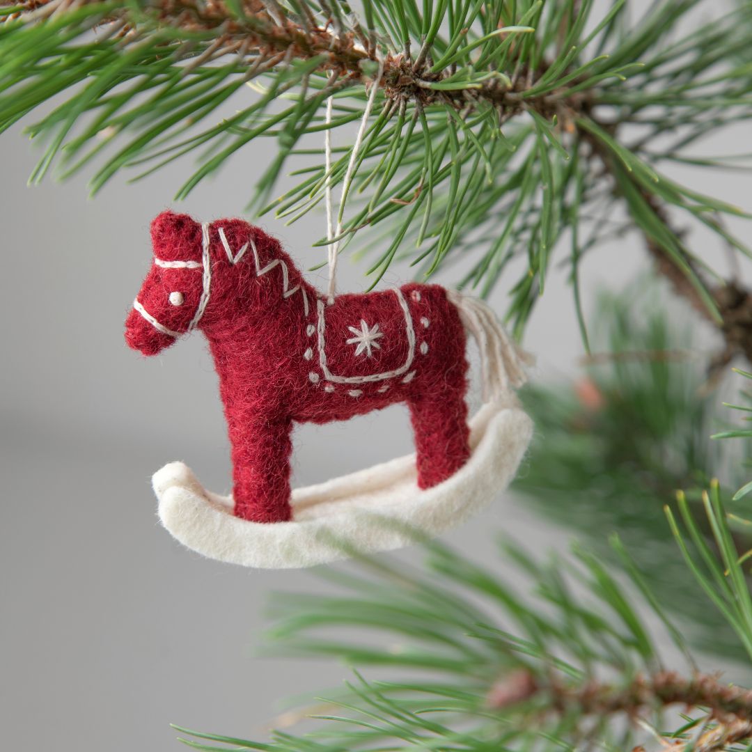 A red and white felt rocking horse with a Christmas tree ornament. By Gry and Sif fair trade handmade