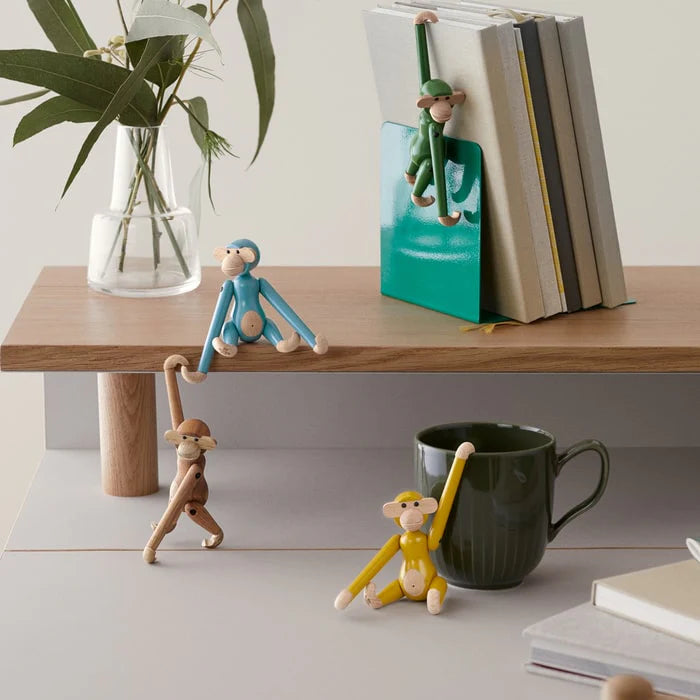 Decorative Kay Bojesen monkey figurines on a table with books and a mug.