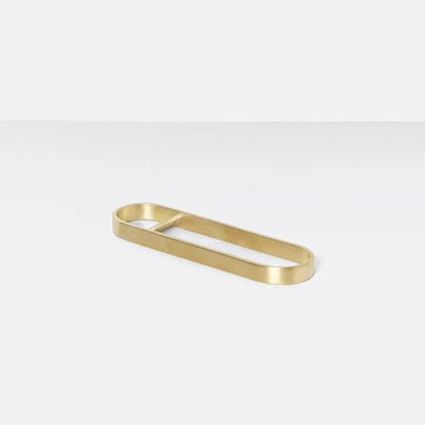 Sleek brass bottle opener on white table.
