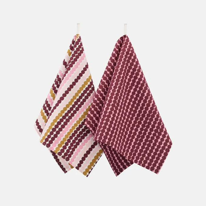 Two patterned kitchen towels hanging from small white loops against a light gray background. One towel has dot stripes in pink, burgundy, and mustard yellow with white backbround, and the other has a burgundy and pink geometric dot pattern.