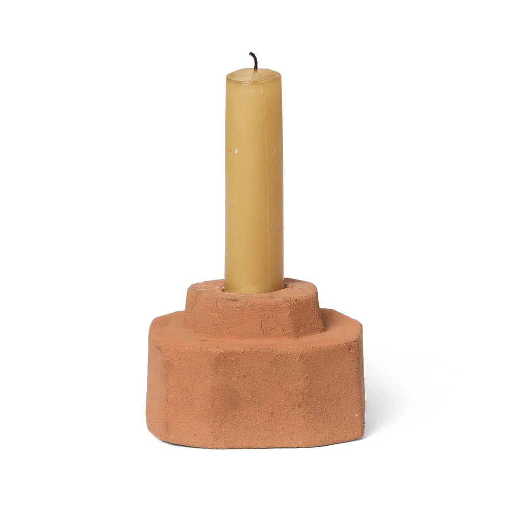 Terracotta candle holder with a yellow candle on a white background