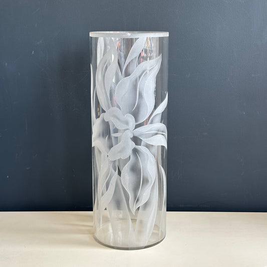 Decorative glass vase with floral etching on a dark background
