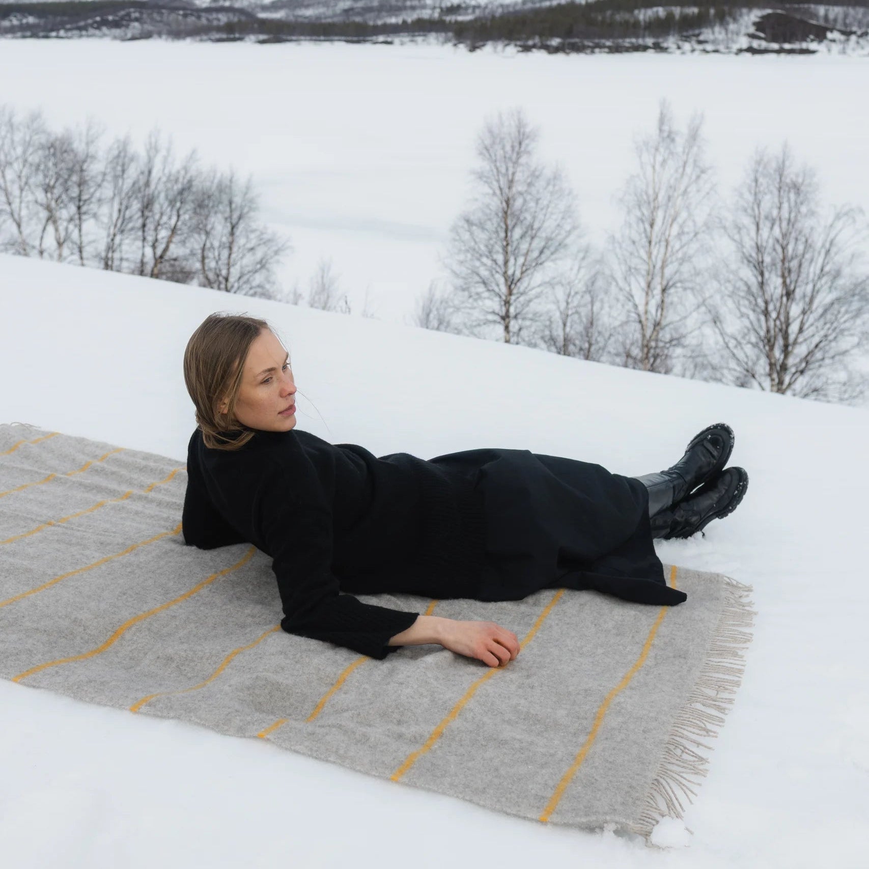 Woman laying on Lapuan Kanurit Wool Blanket in the snow