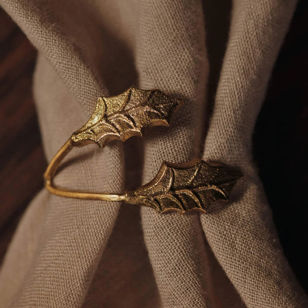 Bronze napkin ring with leaf design on a beige fabric background
