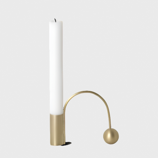 Brass candle holder with white candle.