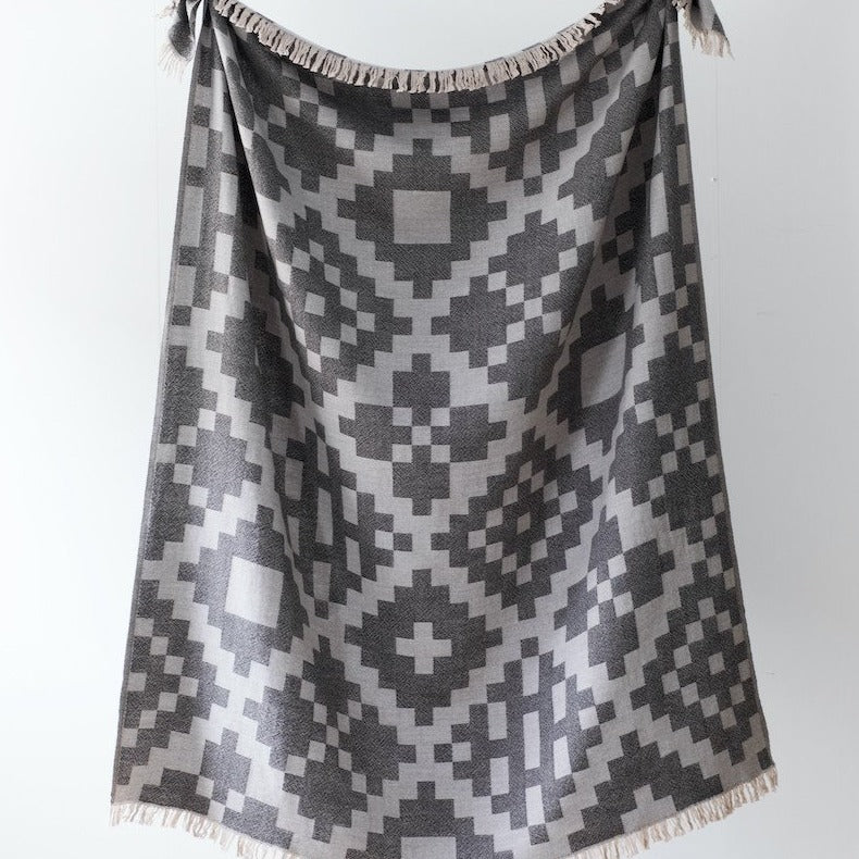 This is a blanket with a light and dark grey geometric pattern.