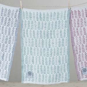 Three multicolored towels with geometric patterns hanging from a clothesline.