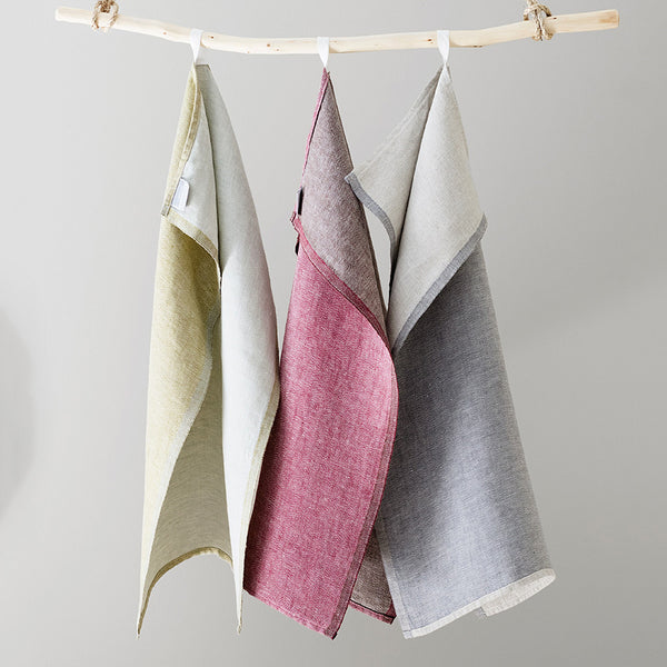 Three colored hand towels hanging from a tree branch.