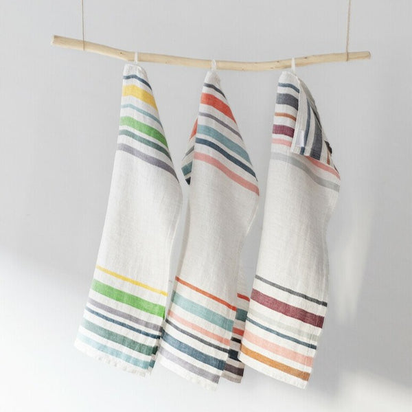Three multicolored striped linen towels hanging from a branch.