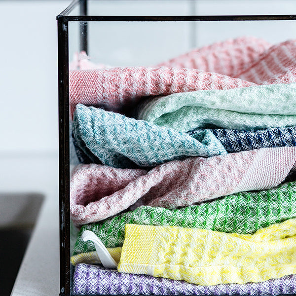 Assorted colors of dishcloths in a glass container.