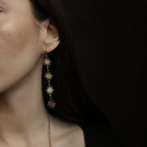 The model is wearing an earring with four starburst patterns.